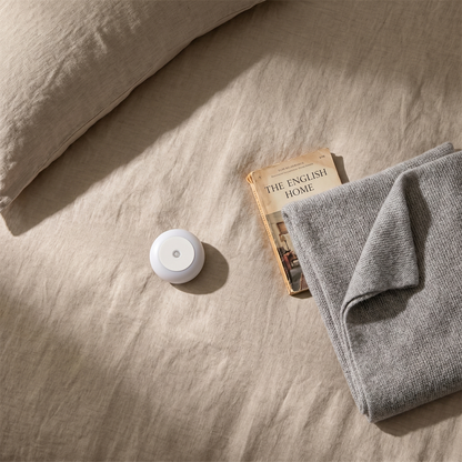 Petty Pet DuskSense Plug-In Night Light flat-lay on linen bedsheet with book and throw