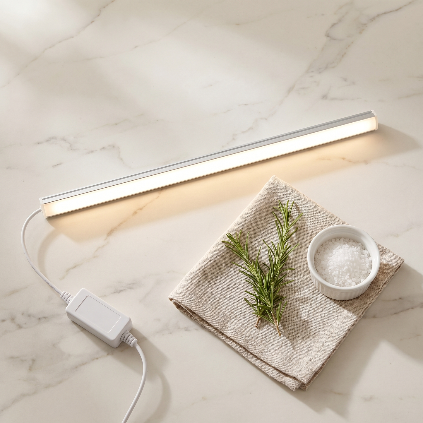 Petty Pet SweepGlow Cabinet Light Bar editorial flat-lay on marble kitchen counter with linen tea towel and rosemary